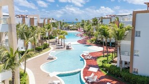A resort with a winding pool, palm trees, and modern buildings. - Blue Beach Punta Cana Luxury Resorts (Punta Cana)