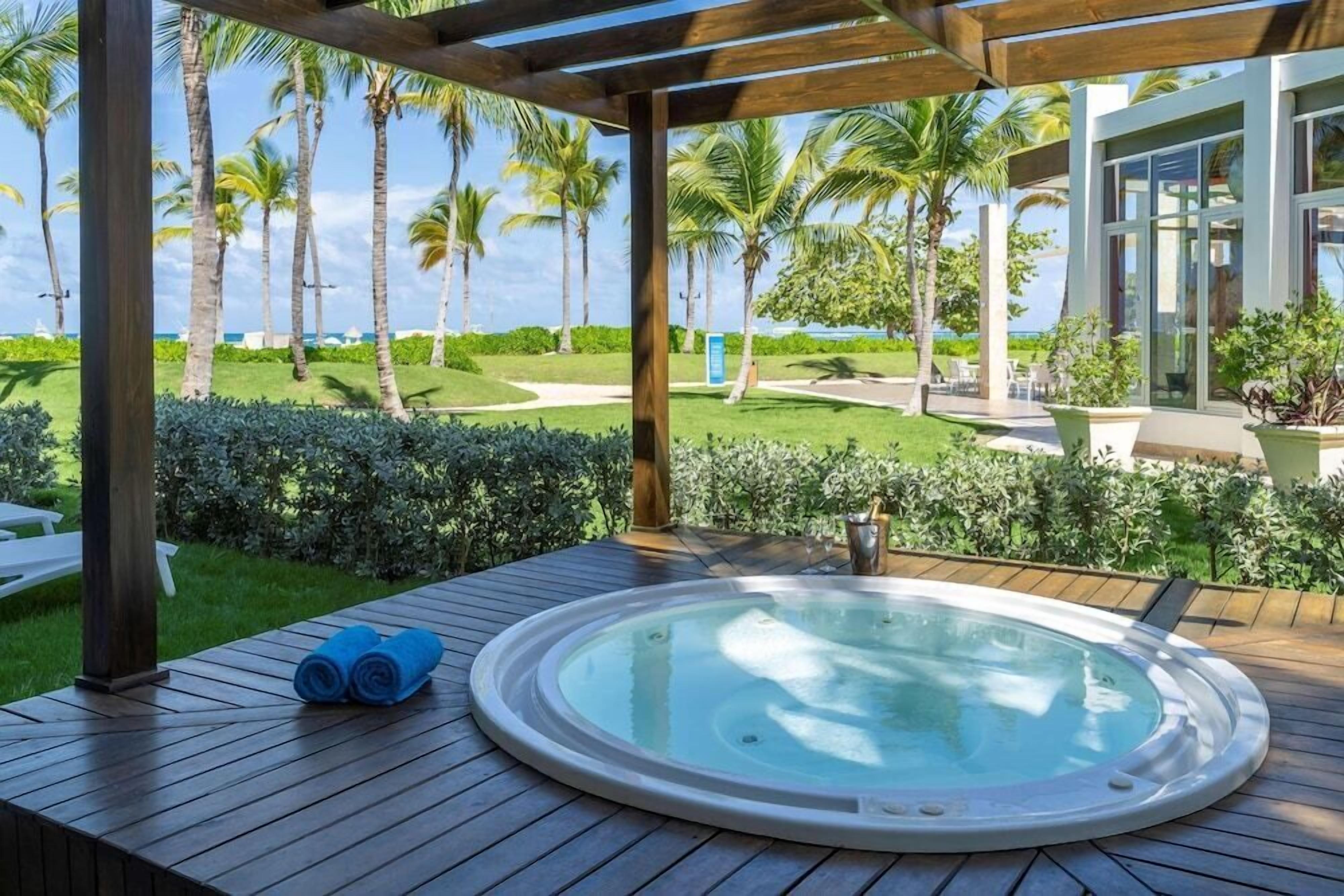 Un bain à remous sur une terrasse en bois, avec vue sur un terrain de golf et des palmiers.