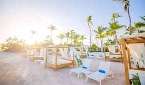 A beach resort with wooden cabanas and white lounge chairs. - Blue Beach Punta Cana Luxury Resorts (Punta Cana)