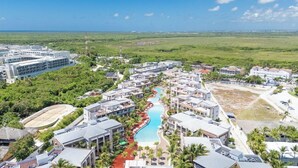 A resort with a central swimming pool, multiple buildings, and a view of the ocean. - Blue Beach Punta Cana Luxury Resorts (Punta Cana)