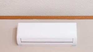 A white air conditioning unit mounted on a wall with a wooden trim.