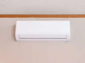 A white air conditioning unit mounted on a wall with a wooden trim. - Capital O Hotel La Siesta, Gomez Palacio (Gomez Palacio)