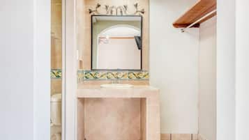 Un baño con piso de baldosas, un lavamanos con espejo y una zona de ducha.