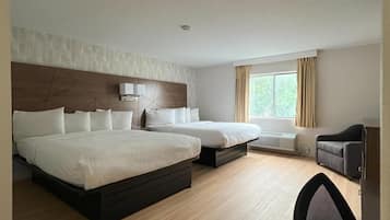 A hotel room with two beds, a desk, a chair, a window with curtains, and a built-in heater.