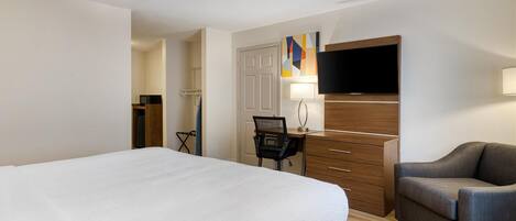 Une chambre d’hôtel avec un grand lit, un bureau avec une chaise, une télévision et un canapé.