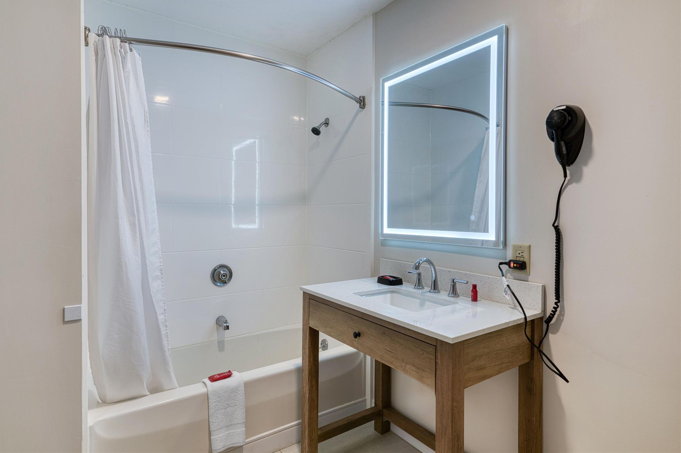 Une salle de bain équipée d’une douche, d’un lavabo, d’un miroir et d’un sèche-cheveux.
