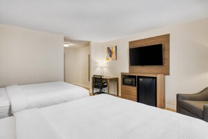 Habitación de hotel con dos camas, un escritorio, televisor y microondas.