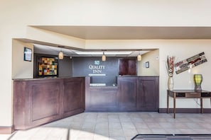Ein Empfangsbereich mit einem dunklen Holzbüro, einer Glastheke und einem Schild für 'Quality Inn by Choice Hotels'.