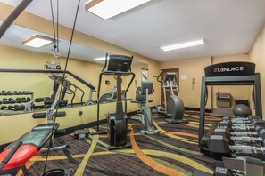 Ein Fitnessraum mit Trainingsgeräten, einer Bank und einem Spiegel.