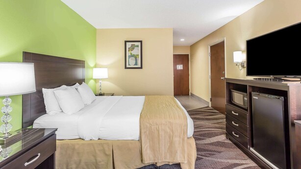 A hotel room with a bed, bedside table, lamp, TV, and a minibar. - Warsaw I-40 (Warsaw)