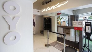 A reception area with a modern design, including a large 'OYO' sign, a glass partition, and a digital display.