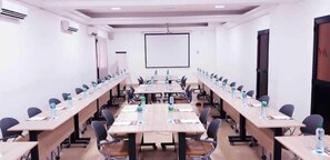 A conference room with long tables, chairs, and a projector screen. - Wakola Hôtel Cheikh Anta (Dakar)