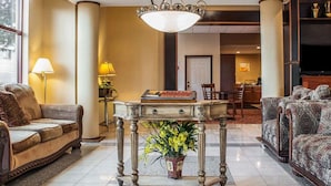 Un salón amplio con candelabro, sofá, una mesa con un florero y televisión al fondo.