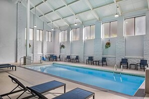 An indoor swimming pool with lounge chairs and tables, large windows, and a high ceiling. - Graystone Lodge, an Ascend Collection Hotel (Boone)