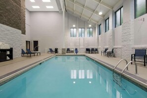 An indoor swimming pool with clear water, surrounded by lounge chairs and a stone wall. - Graystone Lodge, an Ascend Collection Hotel (Boone)