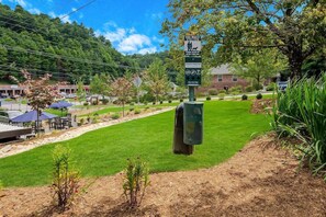 A grassy area with a trash can and a sign indicating a dog waste station. - Graystone Lodge, an Ascend Collection Hotel (Boone)
