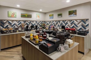 A breakfast bar with various food items and beverages, a coffee station, and decorative wall art. - Graystone Lodge, an Ascend Collection Hotel (Boone)