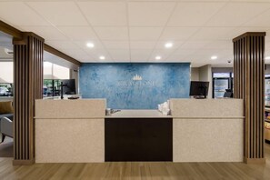 A reception area with a blue wall, a logo, and a counter. - Graystone Lodge, an Ascend Collection Hotel (Boone)