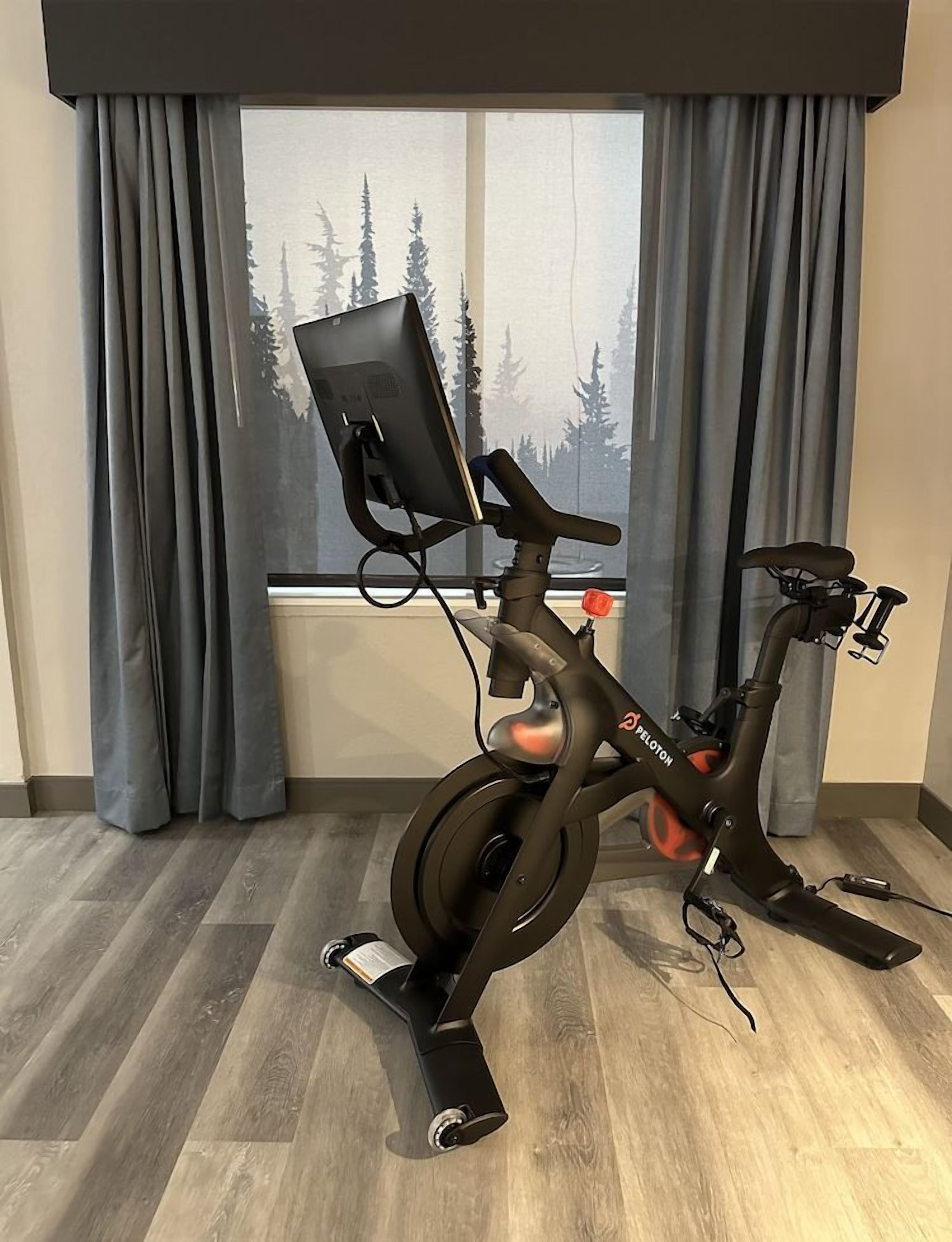 A stationary bike with a digital display, positioned in a room with a window and curtains.