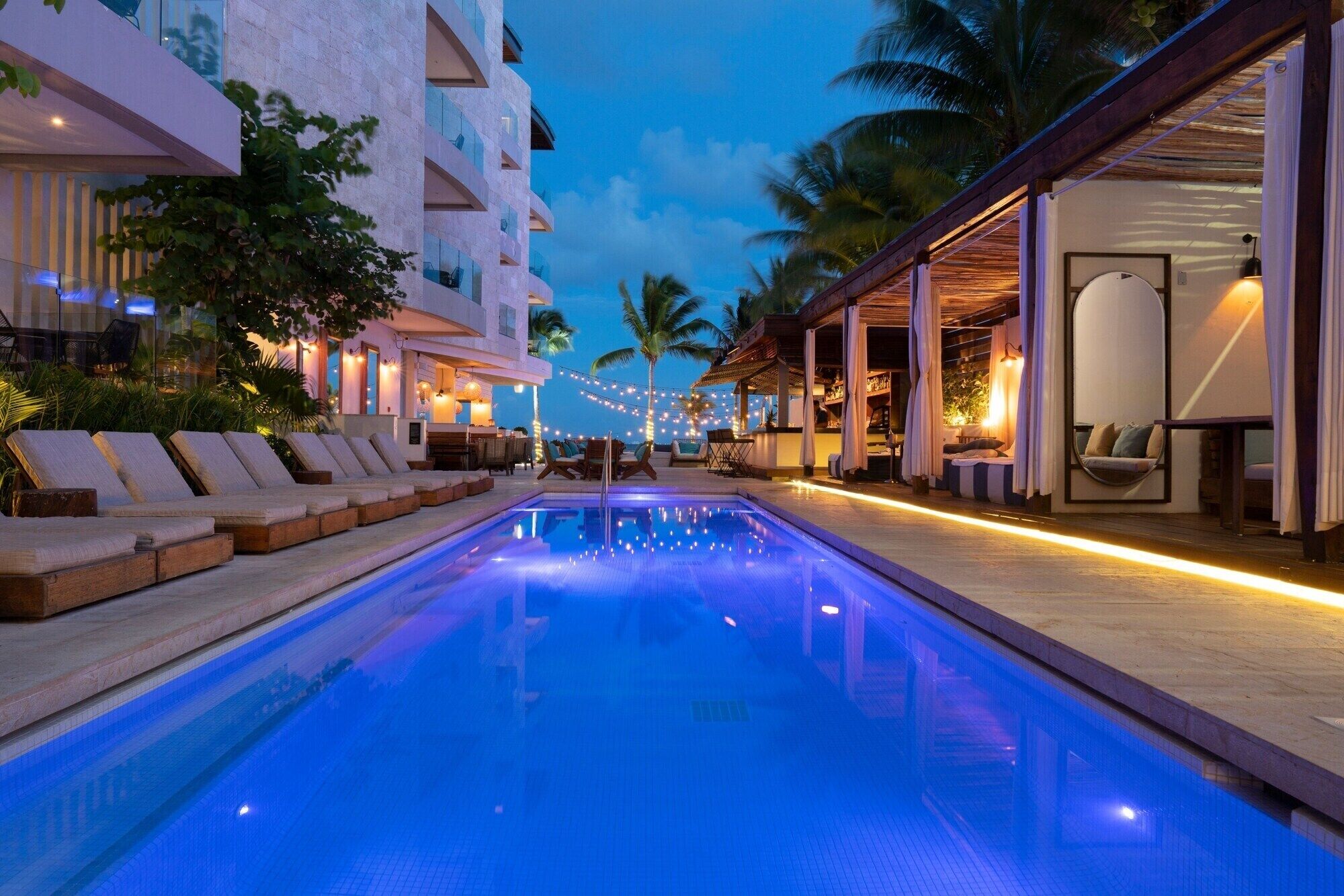 A pool area with lounge chairs and a bar.