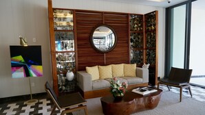 A living room with a sofa, a coffee table, a chair, a round mirror, and a painting. - Thompson Playa Del Carmen Beach House (Playa del Carmen)