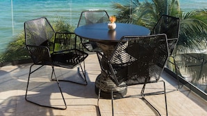 A round table with chairs, a vase with flowers, and a view of the ocean. - Thompson Playa Del Carmen Beach House (Playa del Carmen)