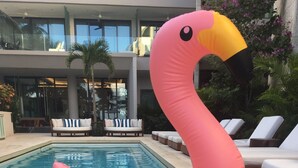 A pool with a pink flamingo float and a dog wearing sunglasses. - Thompson Playa Del Carmen Beach House (Playa del Carmen)
