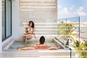 A man in a bathtub with a woman in a bikini sitting on a stone wall. - Thompson Playa Del Carmen Beach House (Playa del Carmen)