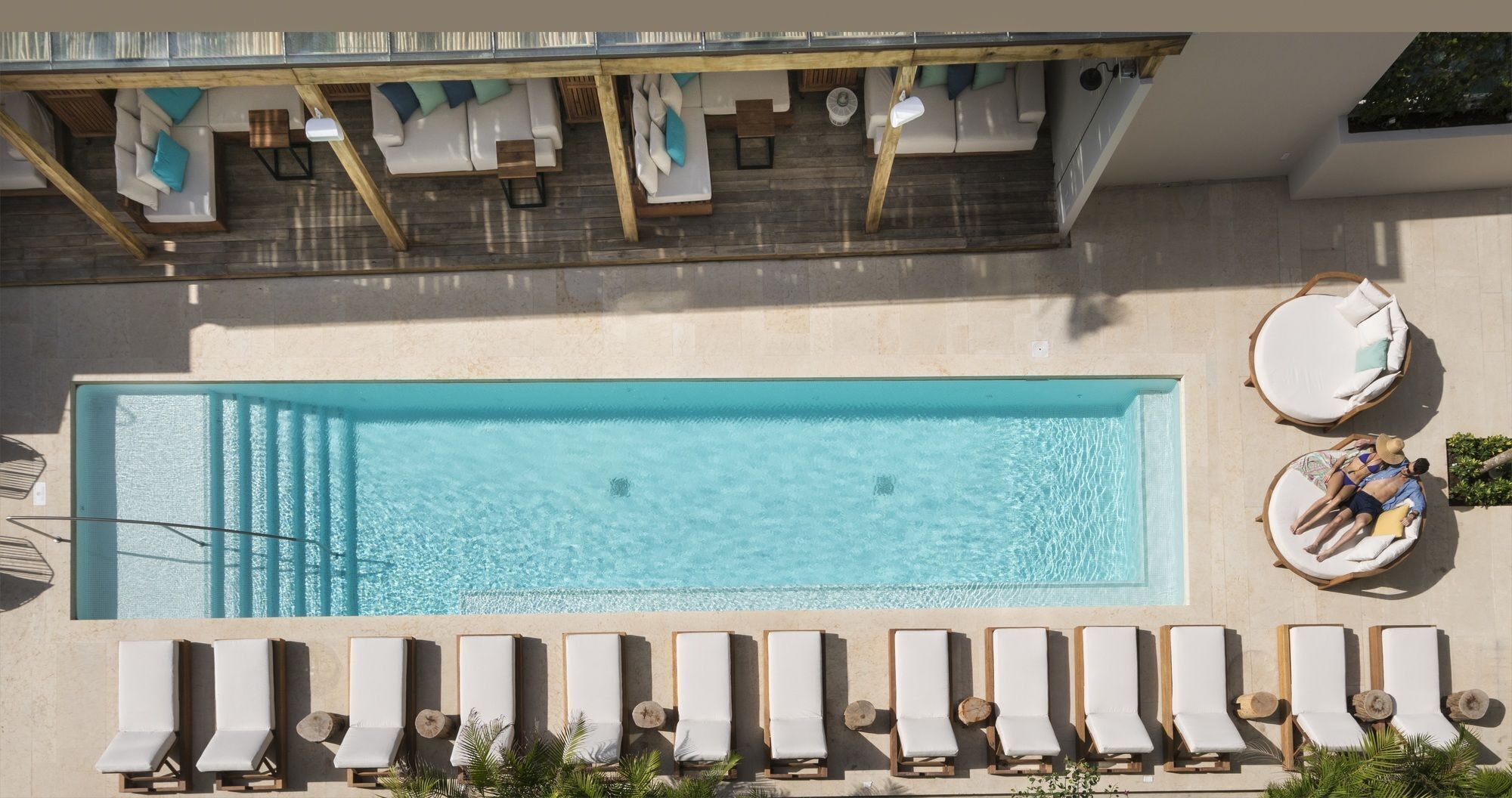 Una piscina rectangular con sillones de jardín y tumbonas alrededor.