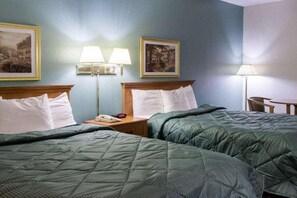 Ein Hotelzimmer mit zwei Betten, einem Nachttisch mit Lampe und Wandbildern.