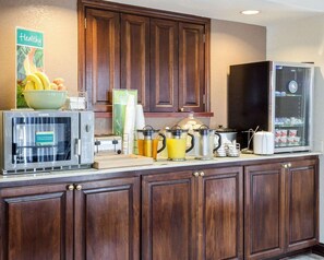 A kitchen with wooden cabinets, a microwave, a refrigerator, and various kitchen appliances. - Quality Inn Magee,ms (Magee)
