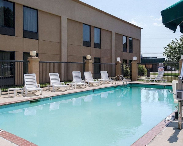 A swimming pool with lounge chairs and a building with large windows in the background.