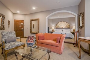 A hotel room with a bed, a sitting area with a sofa and armchair, a glass coffee table, and decorative mirrors. - Quinta Real Saltillo (Saltillo)