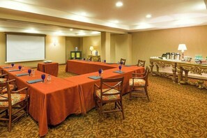 A conference room with long tables, chairs, a projector screen, and a table with various items. - Quinta Real Saltillo (Saltillo)