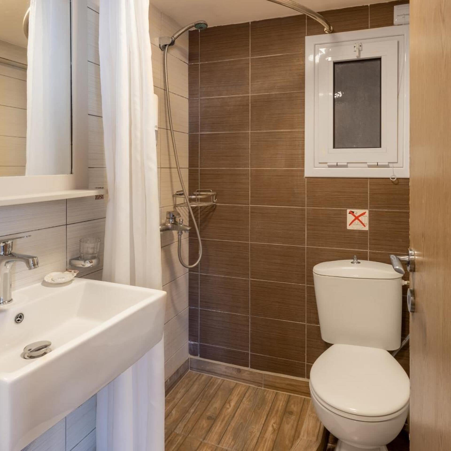 A bathroom with a shower, toilet, sink, and a mirror cabinet.