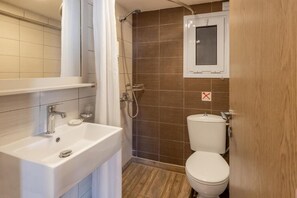 Un baño con lavamanos blanco, ducha e inodoro.