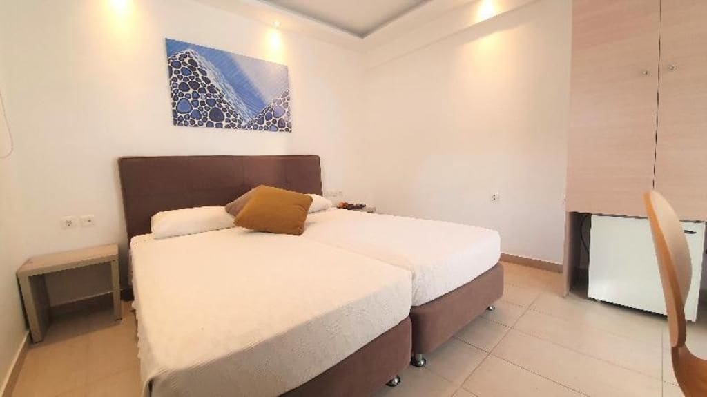 Un dormitorio con dos camas, una mesita de noche, un escritorio y una silla.