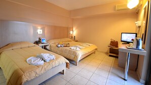 Habitación de hotel con dos camas, un escritorio con ordenador, teléfono y televisor.
