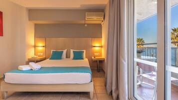 A hotel room with a bed, bedside lamps, a window with curtains, and a view of the sea.