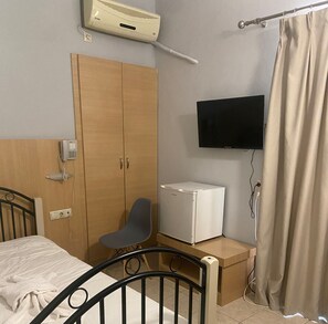 A bedroom with a bed, a wardrobe, a desk with a computer, a TV, and a curtain. - Kos City Sunstone Hotel (Kos)