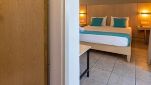 Una habitación de hotel con una cama, mesitas de noche y un aire acondicionado de pared.