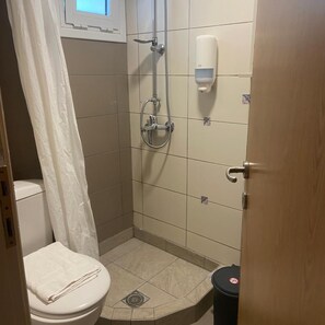 A small bathroom with a toilet, shower, and a hand soap dispenser. - Kos City Sunstone Hotel (Kos)
