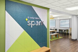 A modern office space with a geometric wall design, a motivational quote, and a view of a dining area with tables and chairs. - Spark by Hilton Beckley (Beckley)