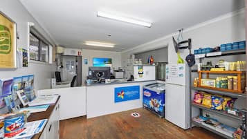 A small, well-lit room with a counter, a refrigerator stocked with snacks, and a display of travel brochures.