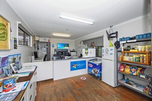 A small, well-lit room with a counter, a refrigerator stocked with snacks, and a display of travel brochures.