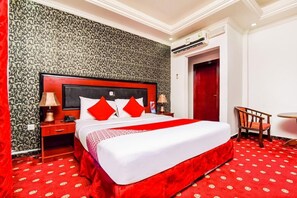 A hotel room with a large bed, a nightstand, a chair, and a small table. - Gulf Star Hotel Deira (Dubai)