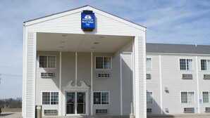 A two-story building with a covered entrance, a sign indicating it is an America’s Best Value Inn, and a handicap-accessible parking sign.