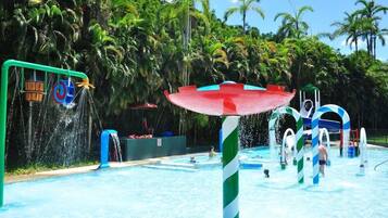 Een waterpark met een zwembad, glijbanen en een grote parasolstructuur.