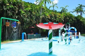 Parque aquático com piscina, toboáguas e uma grande estrutura em forma de guarda-sol.