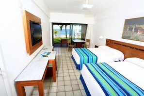 Habitació d'hotel amb llit, escriptori, cadira, televisió i vista a la platja.